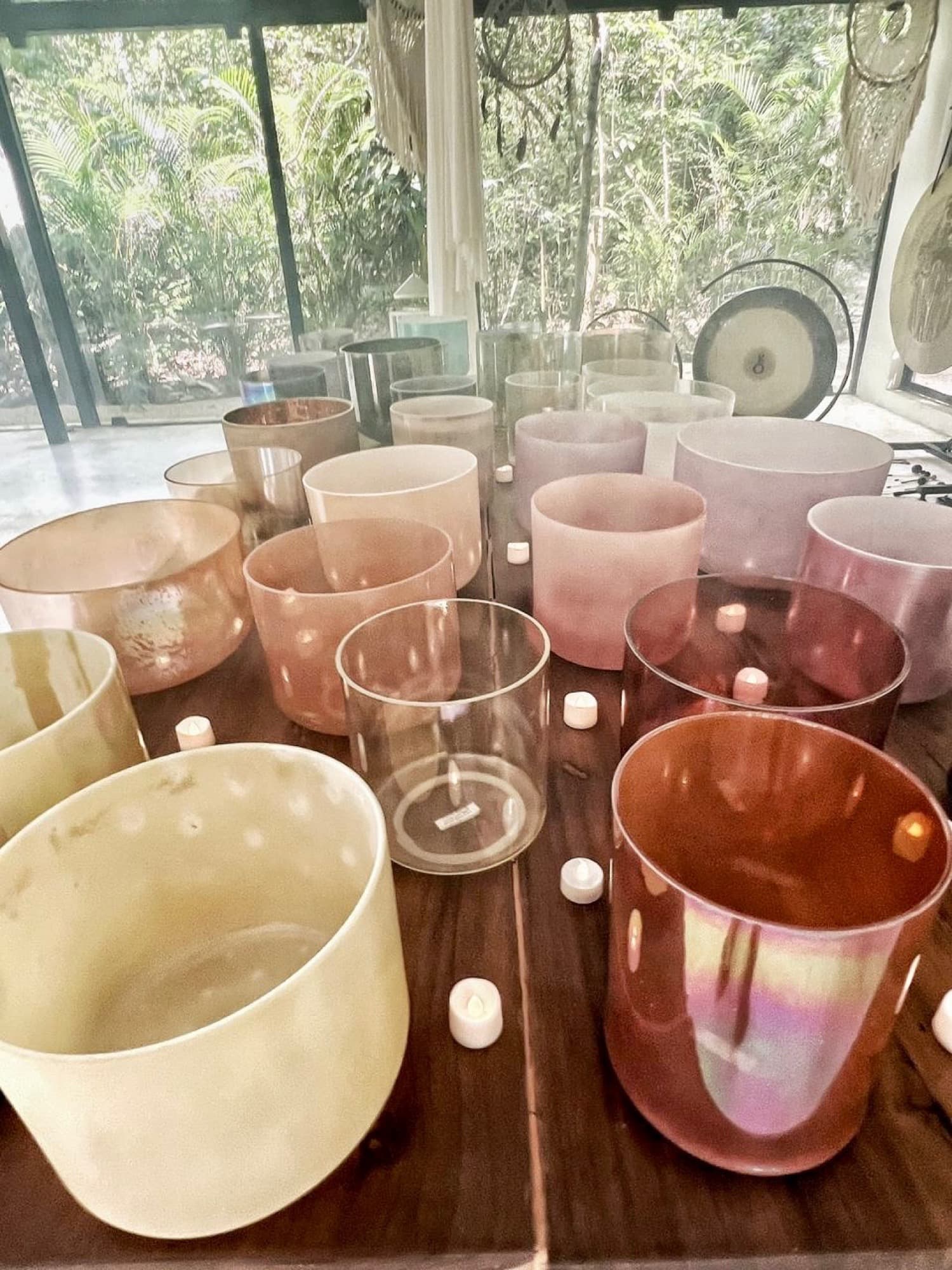 Crystal alchemy bowls close on the wooden table, the gong blurred behind