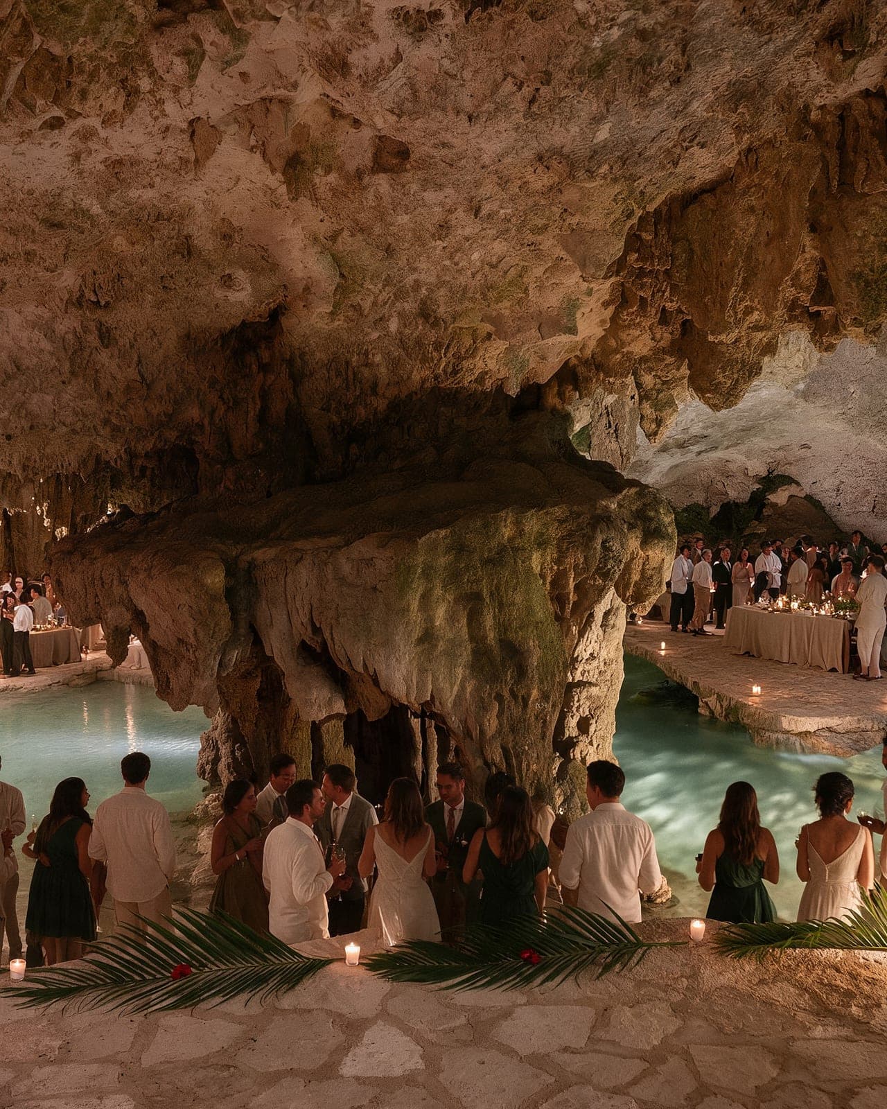 Guests gathered around the cenote at a celebration, candlelight across the rock