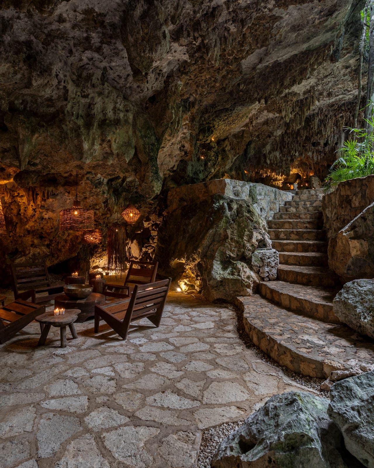 The candlelit cave lounge, wooden chairs and a singing bowl beneath glowing wicker lanterns