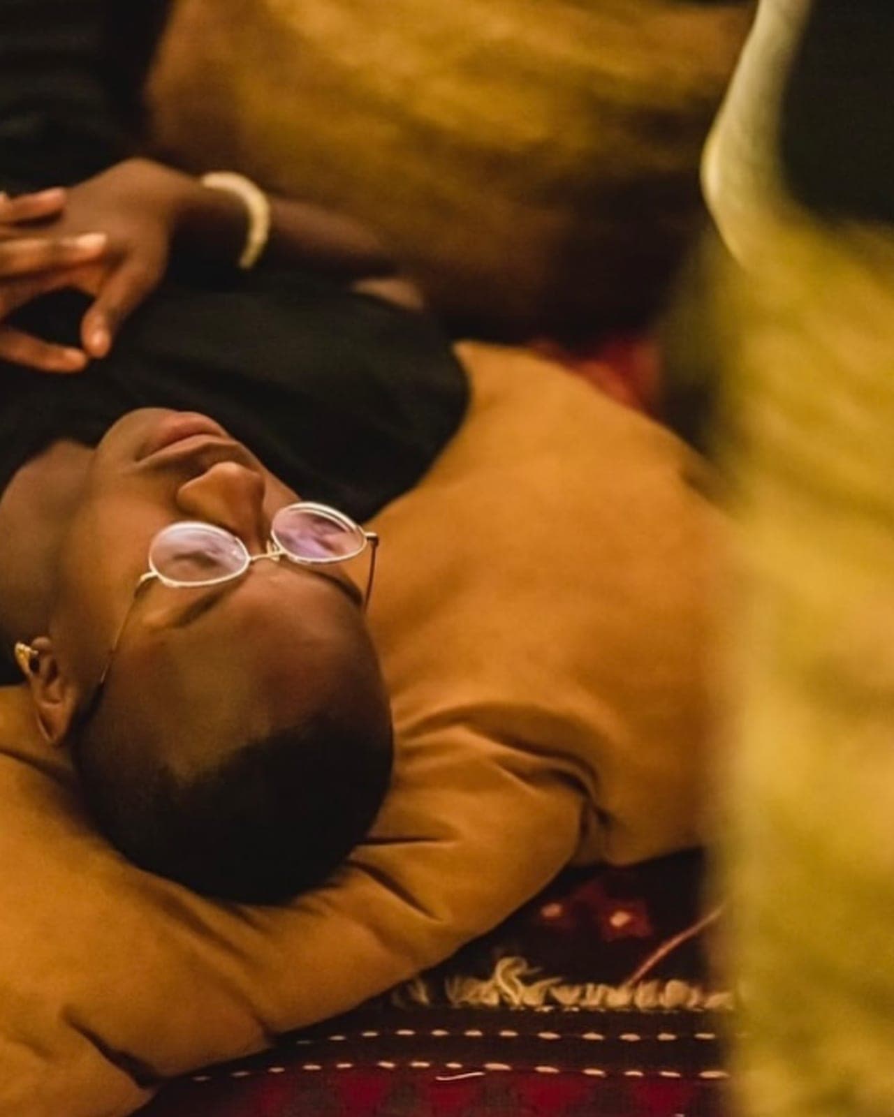 A guest resting in an ochre robe, eyes covered, during a sound journey