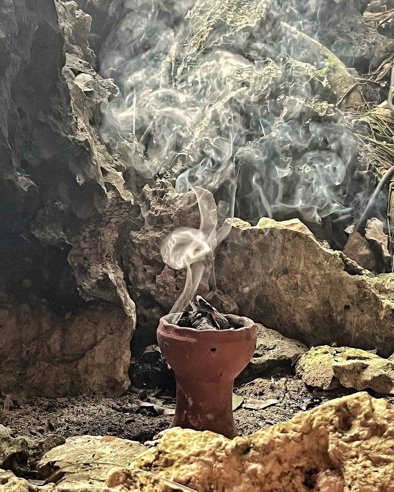 Copal smoke rising from a clay burner set on the limestone
