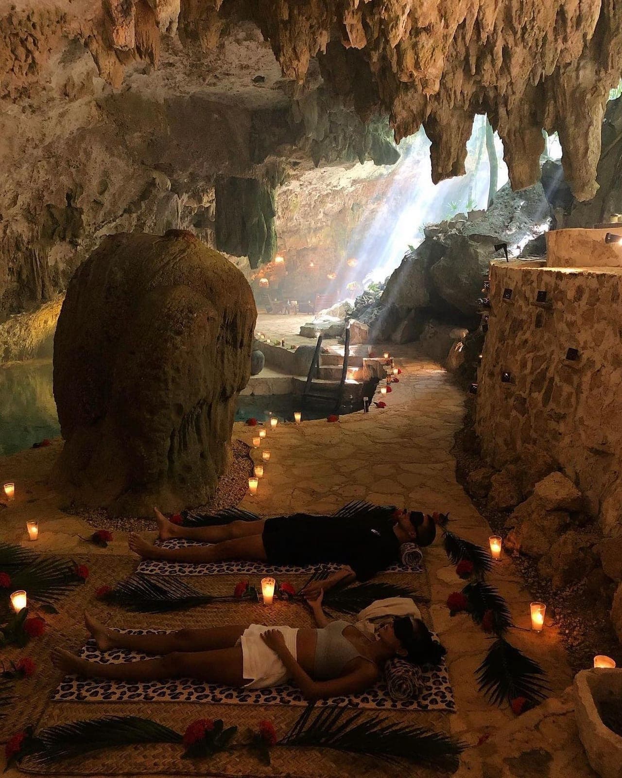 Guests lying on mats as a shaft of daylight falls through the opening in the cave