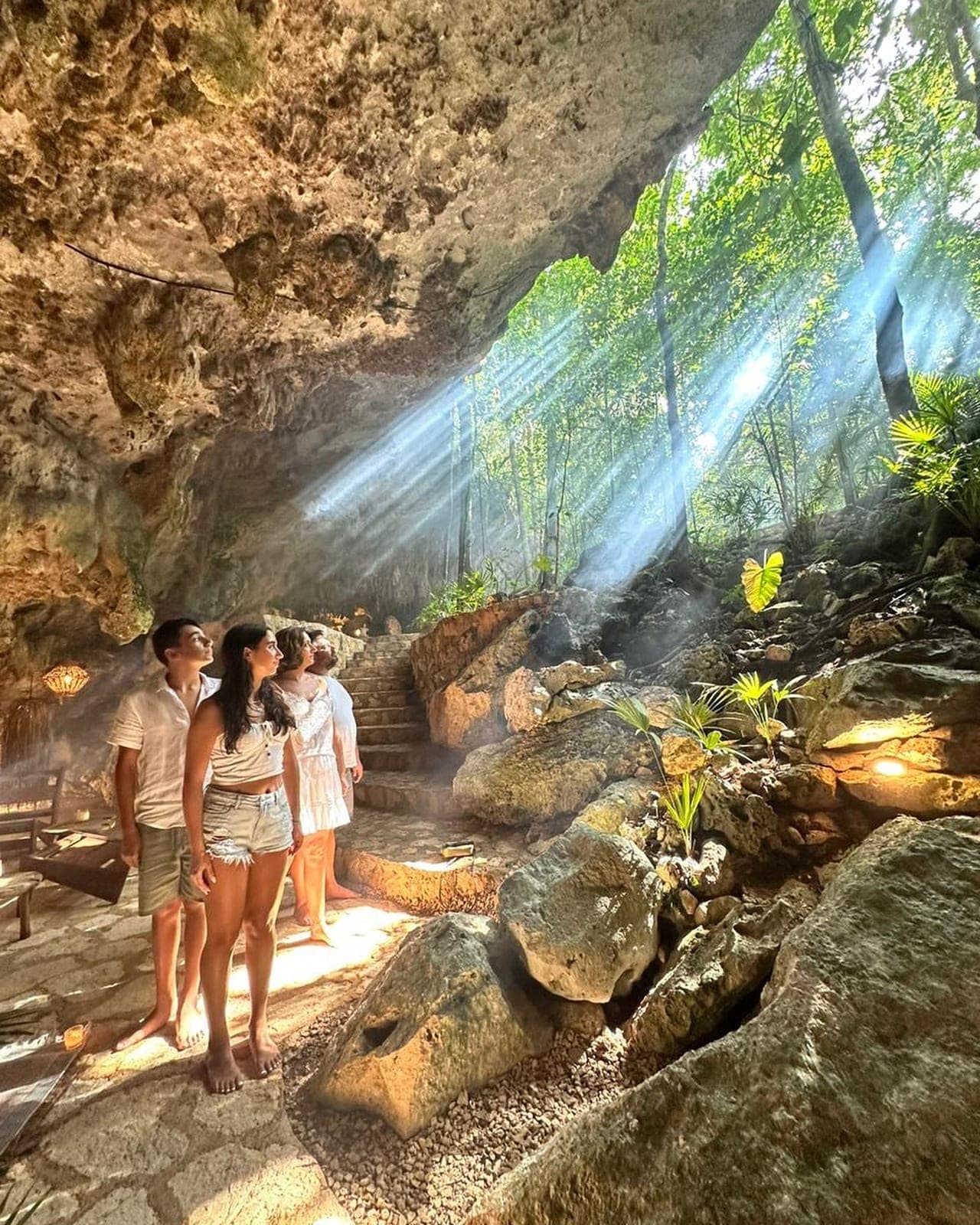 Three guests walking the rocks in a shaft of jungle light