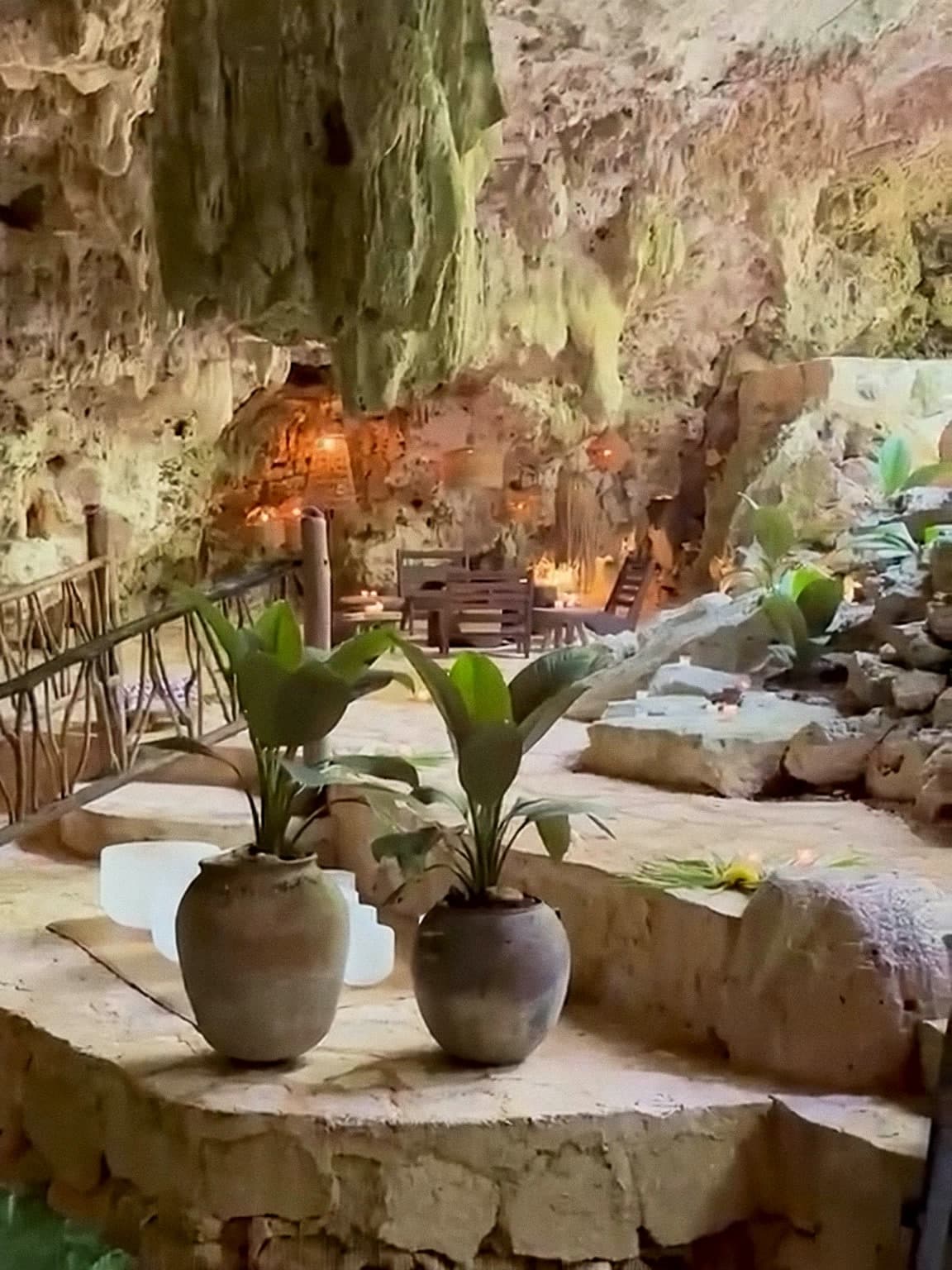 A guest floating on a mattress on the cenote while a Medicine Musician plays from the stone ledge above the water