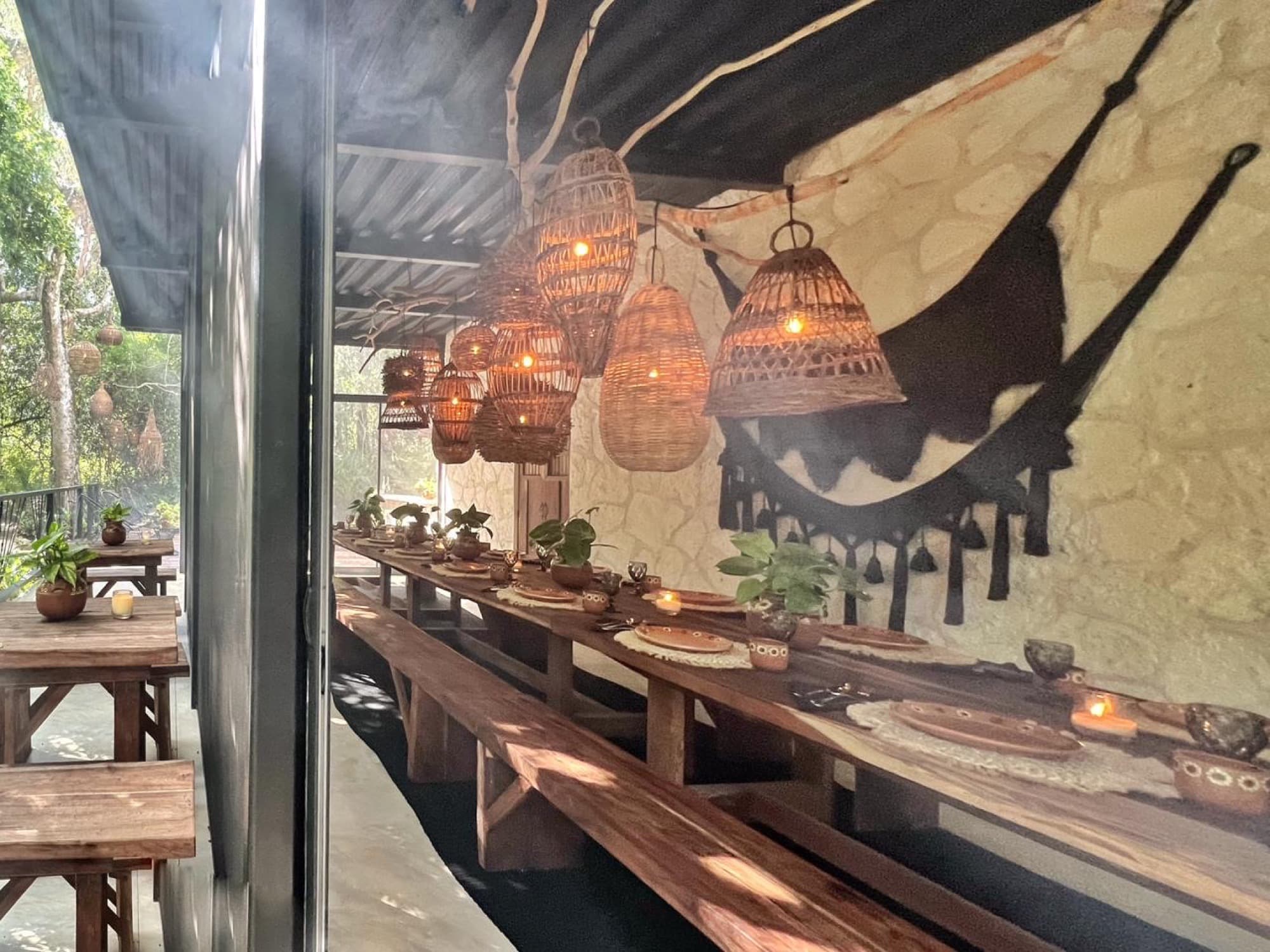 The stone wall with its black hammock, lanterns lit along the table