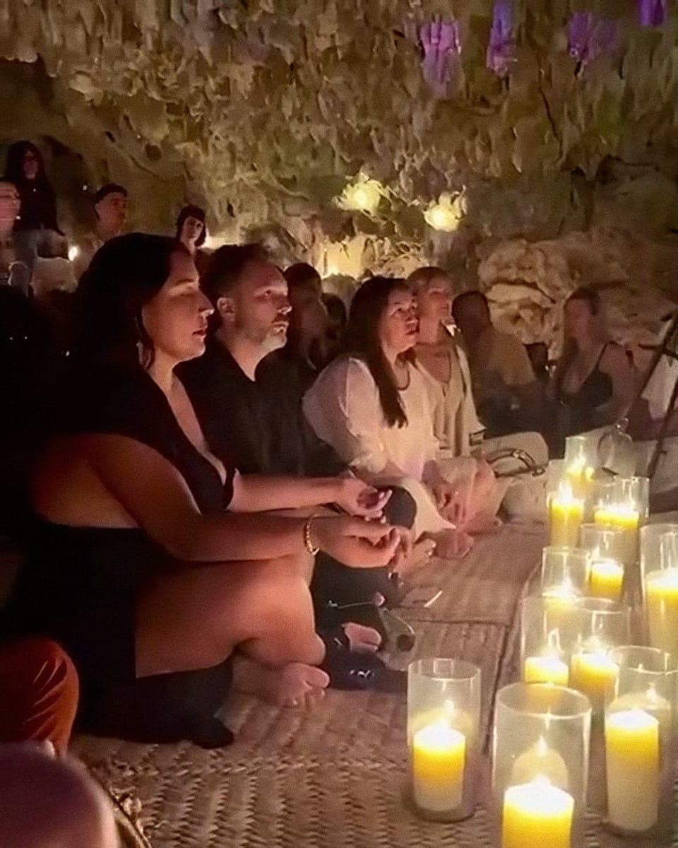 Guests gathered at the candlelit ceremony table in the cave, faces warm in the light