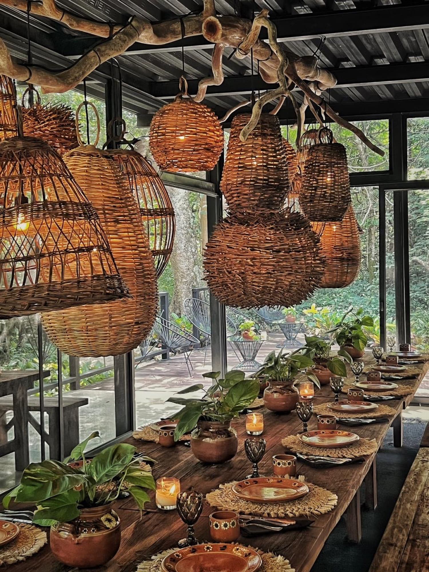 Woven basket lanterns hung from a branch over the set table, candles already lit