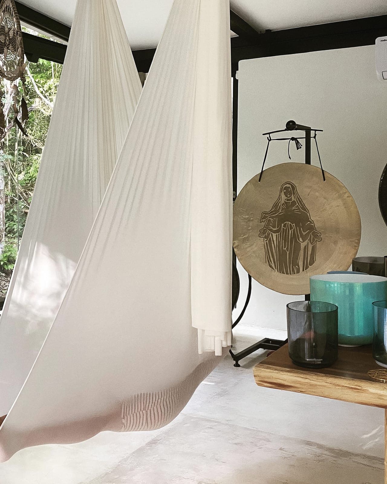 A guest cocooned in a white silk hammock beside the crystal bowls and the engraved gong