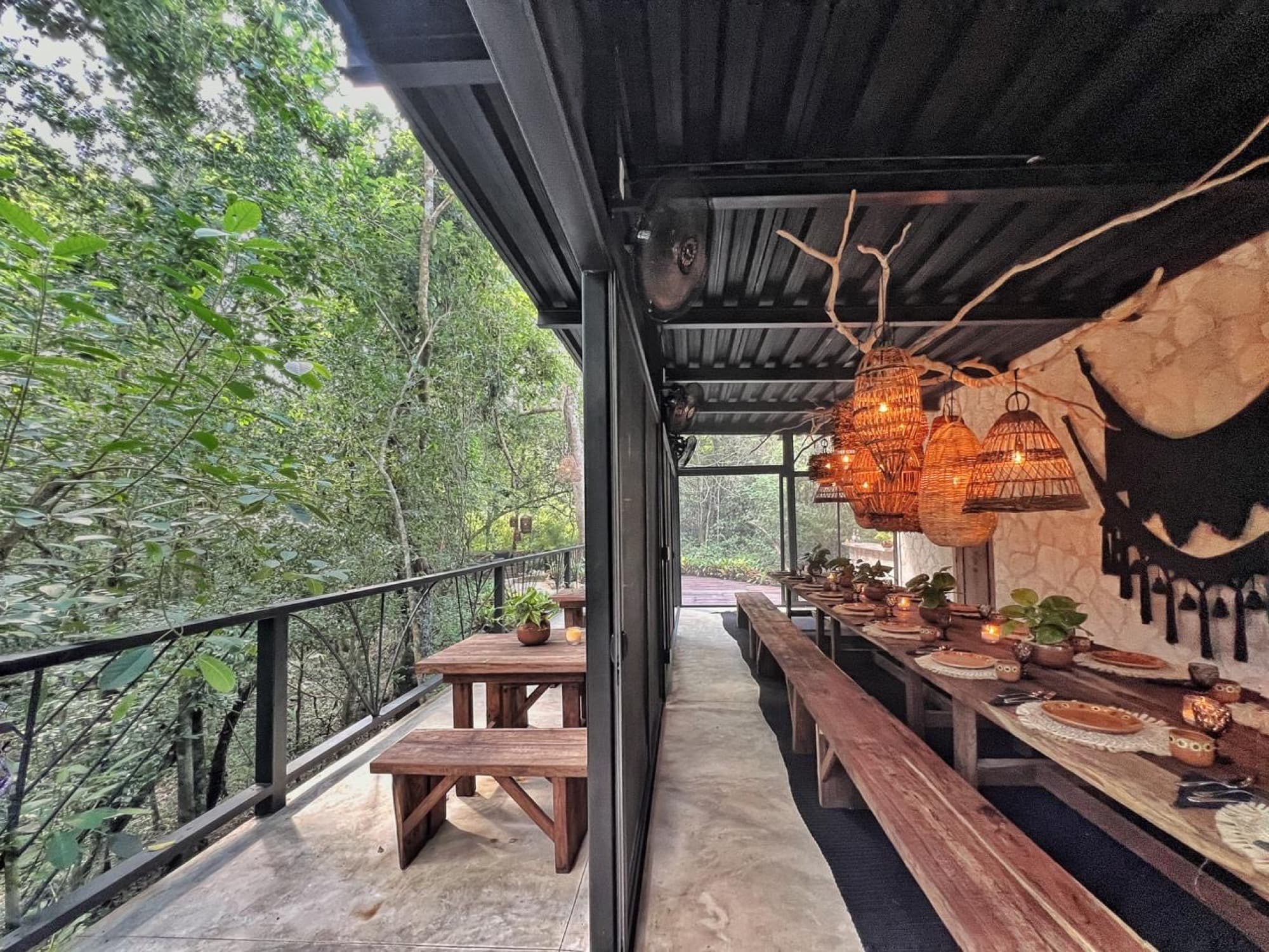 The whole room from the rail: benches, the laid table and the jungle falling away below