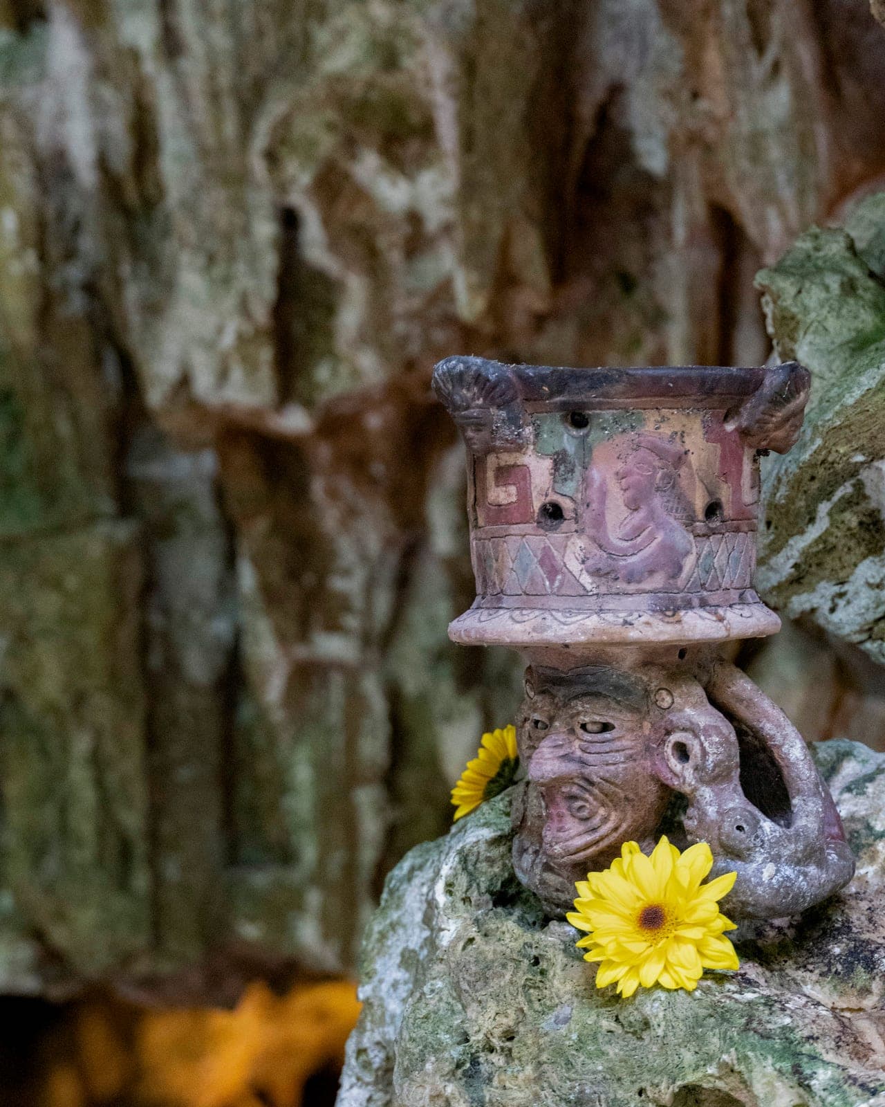 Un sahumador maya de barro con forma de efigie coronado de crisantemos sobre la roca de la cueva