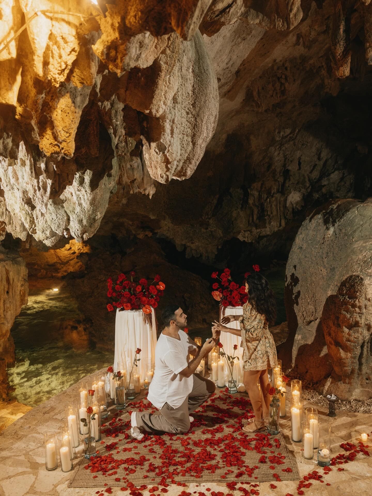 A proposal on one knee in the cave, red roses and a ring of candles on the floor