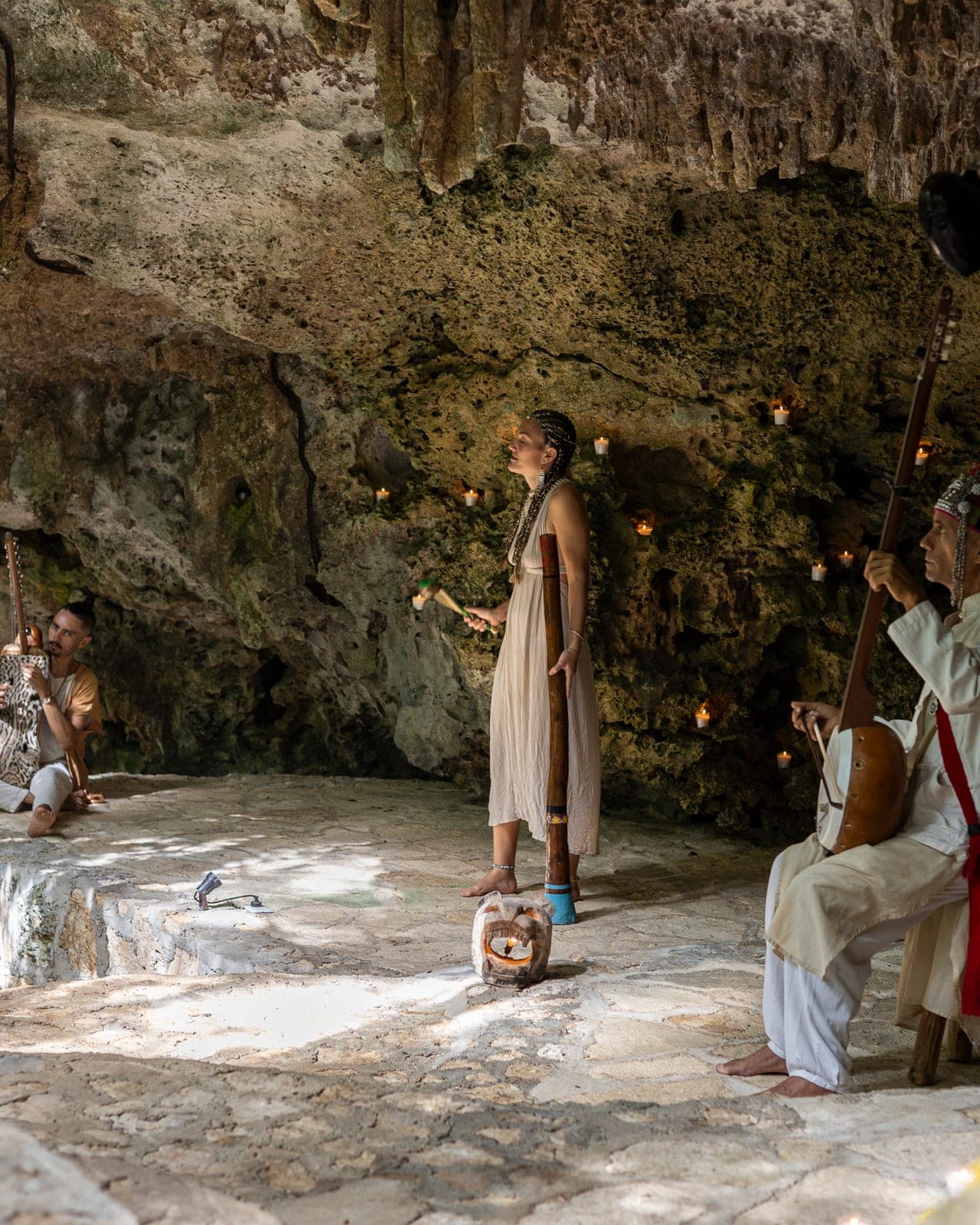 Three Medicine Musicians on the stone platform of the cave, a didgeridoo standing between seated string players