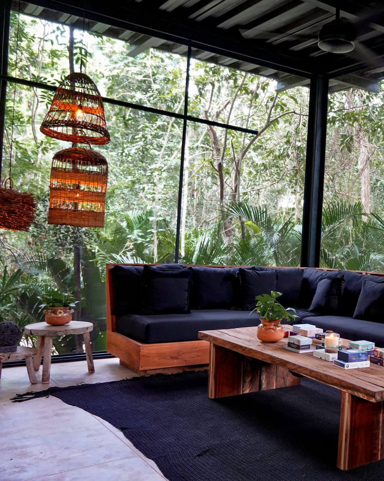 The reception lounge: black sofas, oracle decks on the wood table and the jungle through the glass