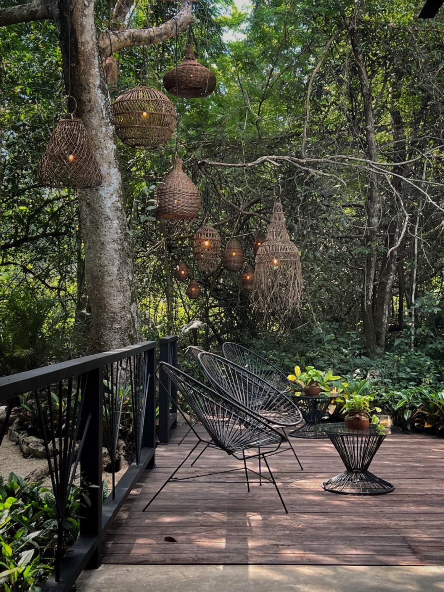 Two woven chairs on the terrace deck under hanging baskets, jungle all around
