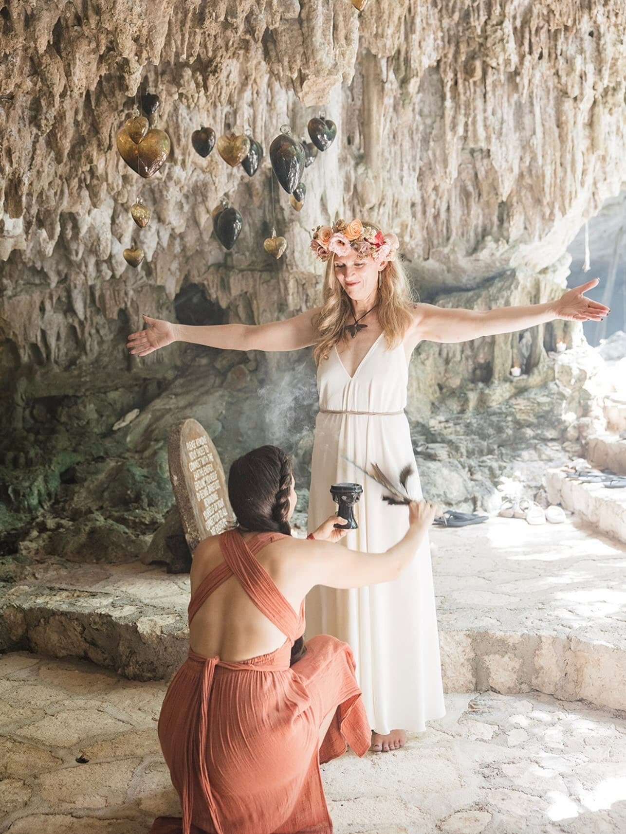 A bride blessed with copal smoke in the cave, glass hearts hanging from the rock above her