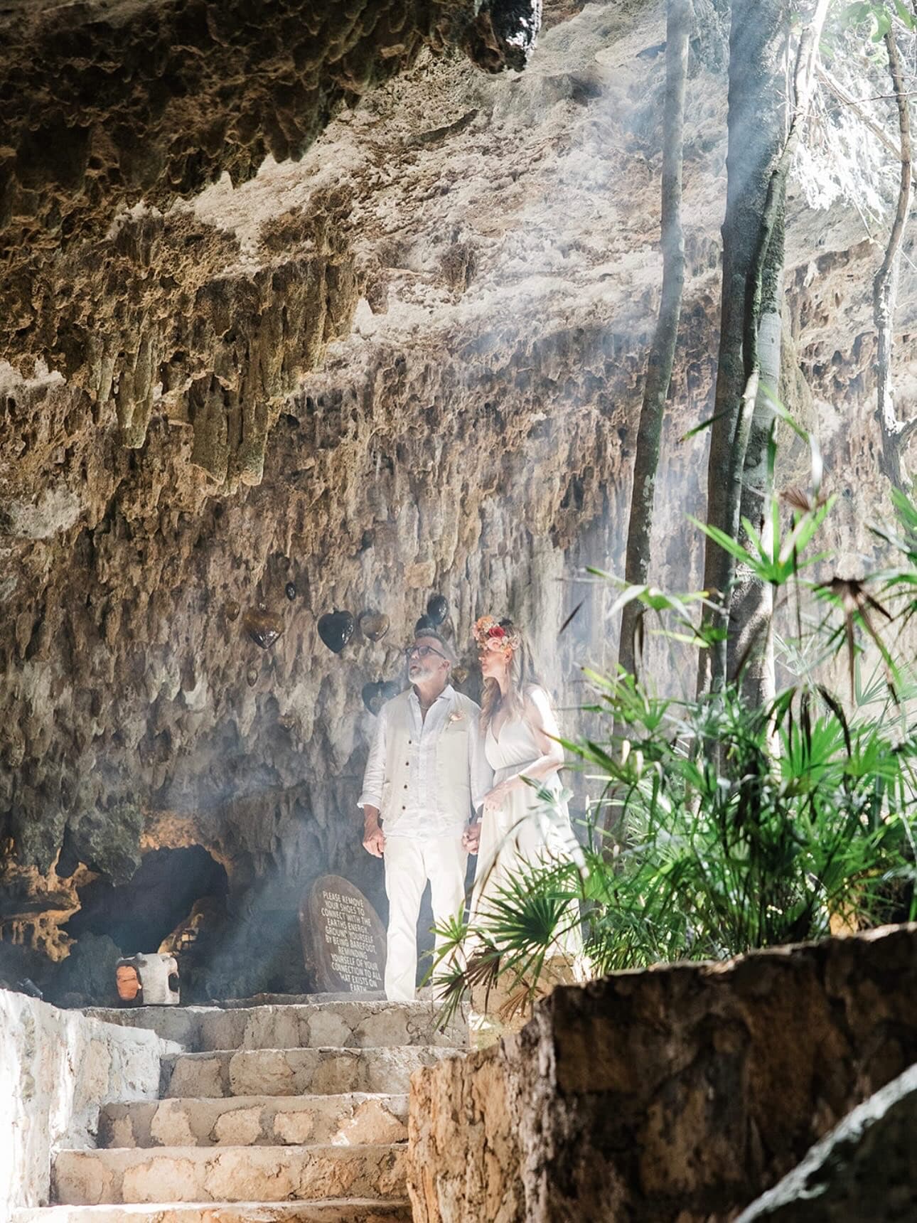 A couple coming down into the cave through the copal smoke, the stone stair ahead of them
