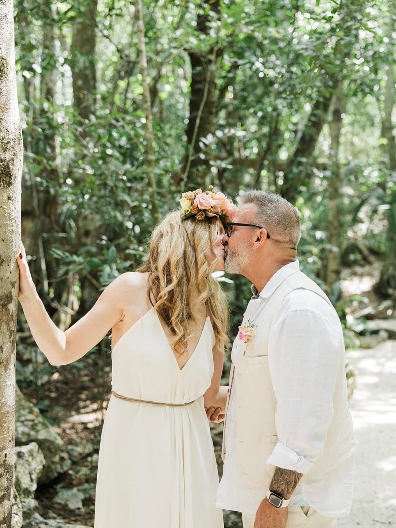 A couple kissing beneath the jungle canopy, the bride in a flower crown