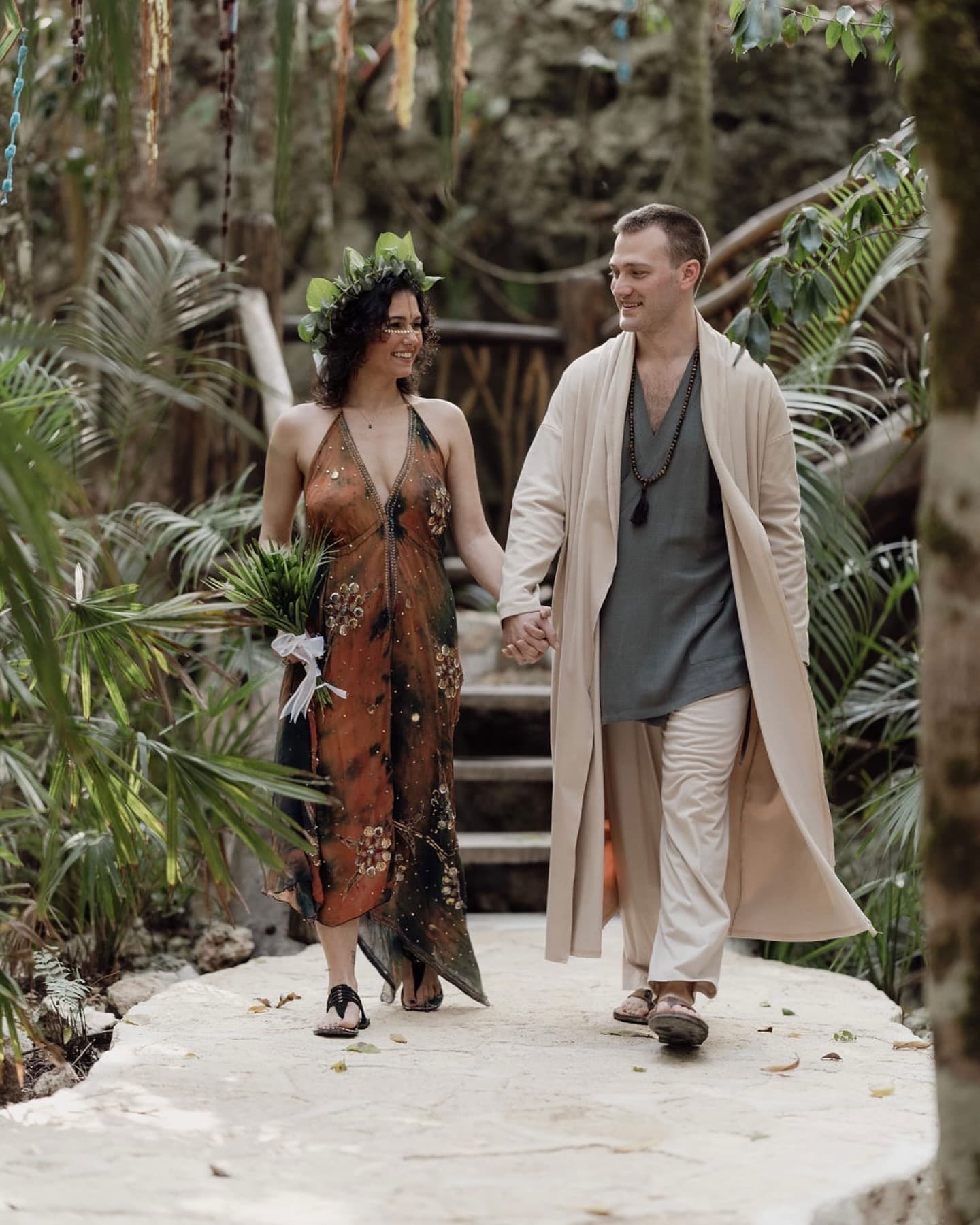 A couple walking the jungle path together after their ceremony, palms on both sides