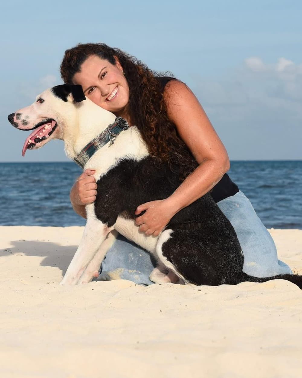 Ana Paola on the sand with her dog, the sea behind them