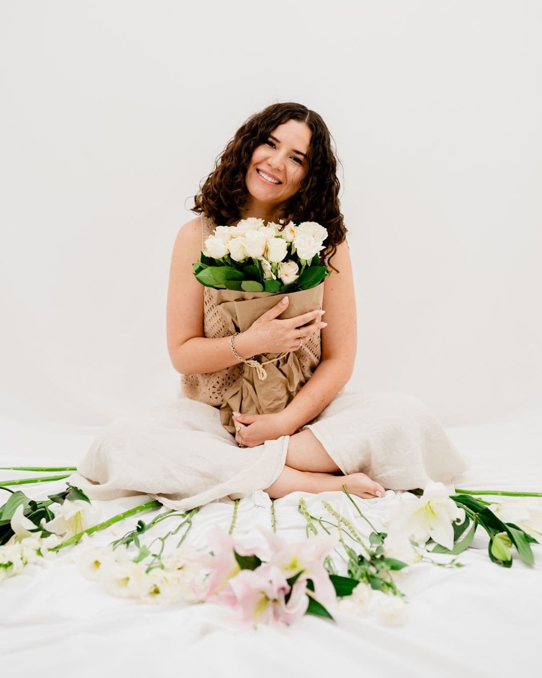 Julia Salinas seated among white roses and lilies, holding a bouquet