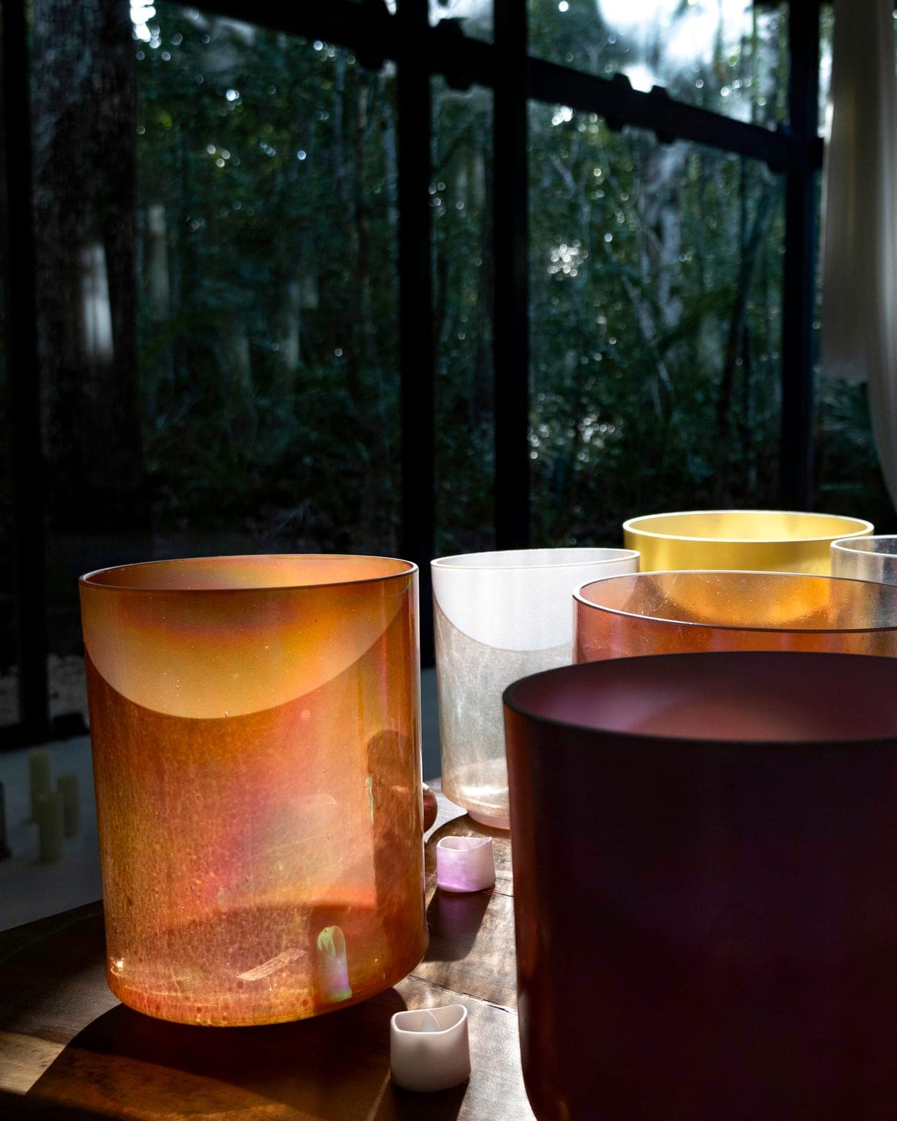 Crystal alchemy bowls glowing amber and violet in the darkened temple, white silks behind