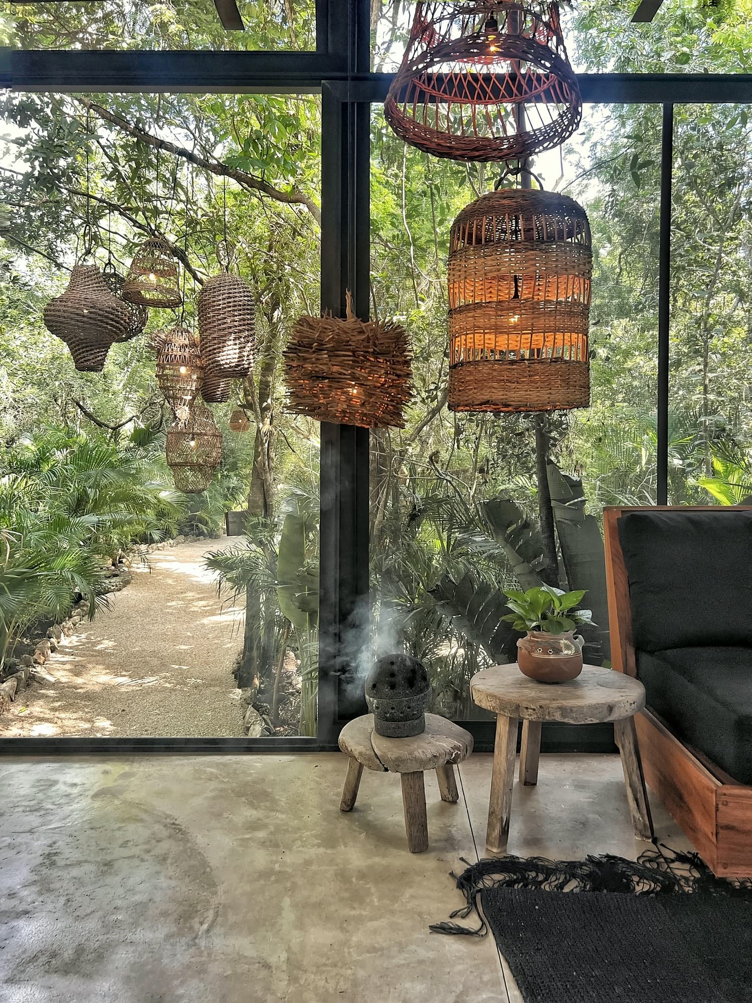 A cluster of woven lanterns hanging inside La Recepción, copal smoke drifting past the glass and the jungle path beyond