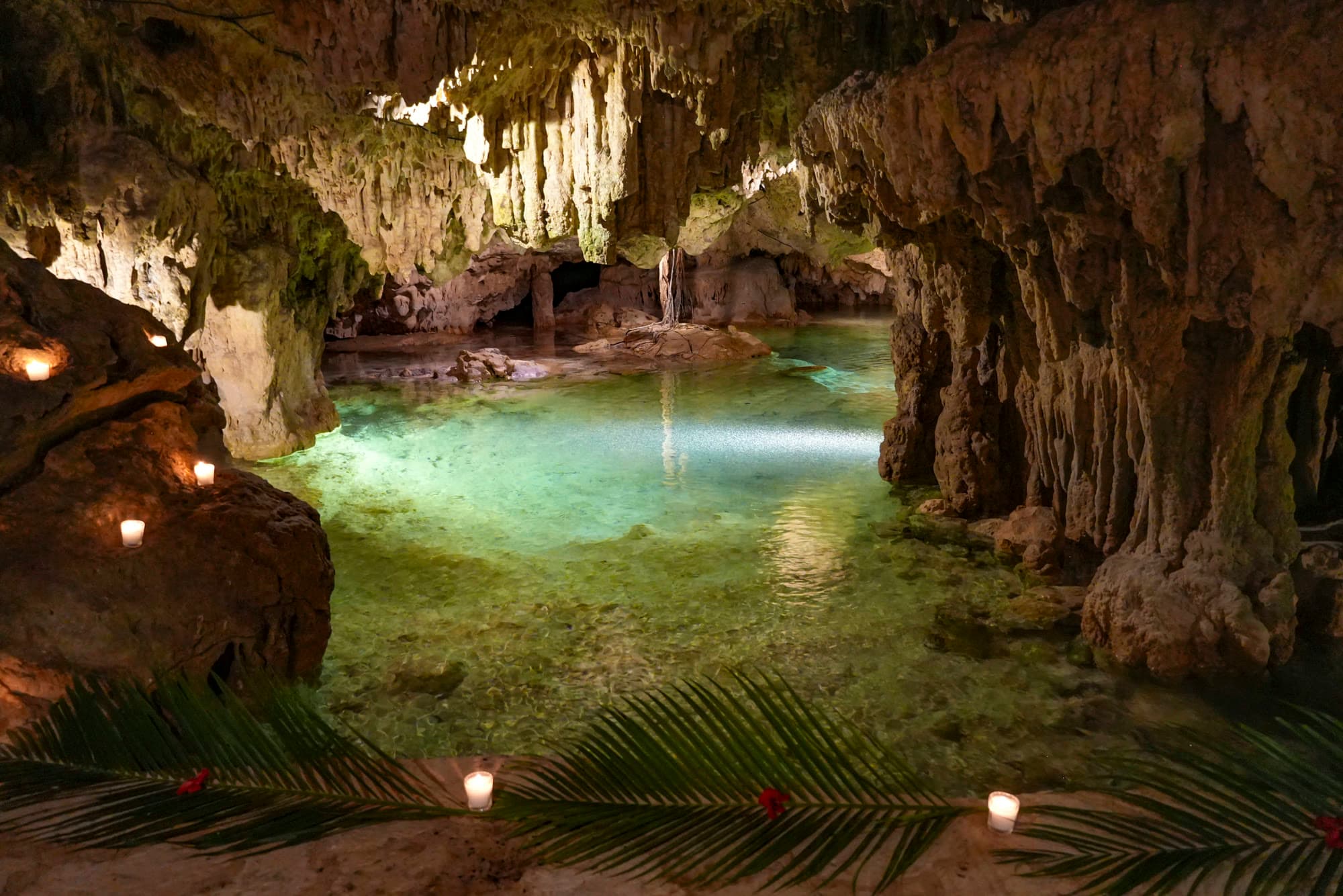 The Water Temple: stalactites hanging the length of the cave above the clear turquoise pool, candles along the stone